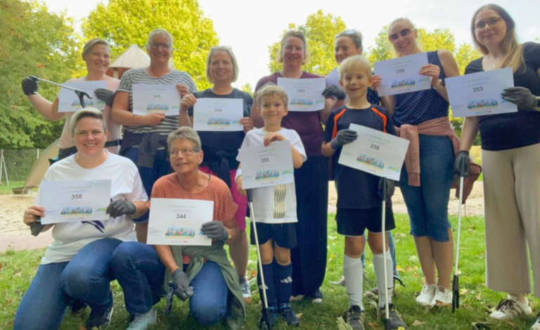 Eine Gruppe von Erwachsenen und Kindern hält Urkunden einer Plogging-Aktion des KreisSportBund Diepholz in die Kamera.