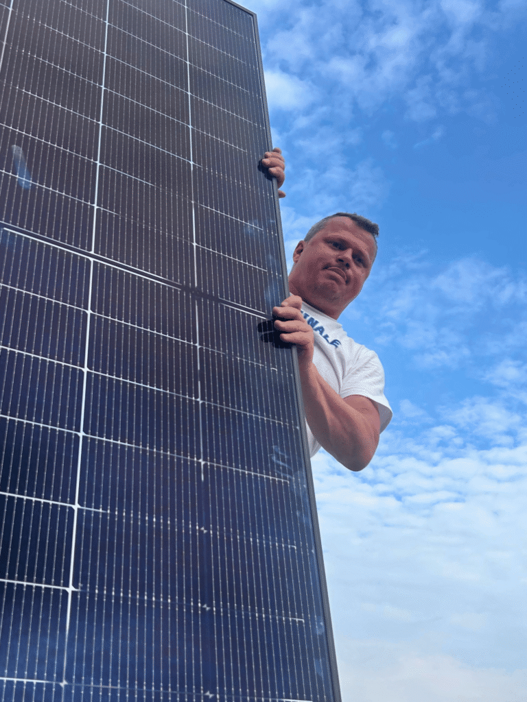 Mann präsentiert Balkon-Solaranlage.