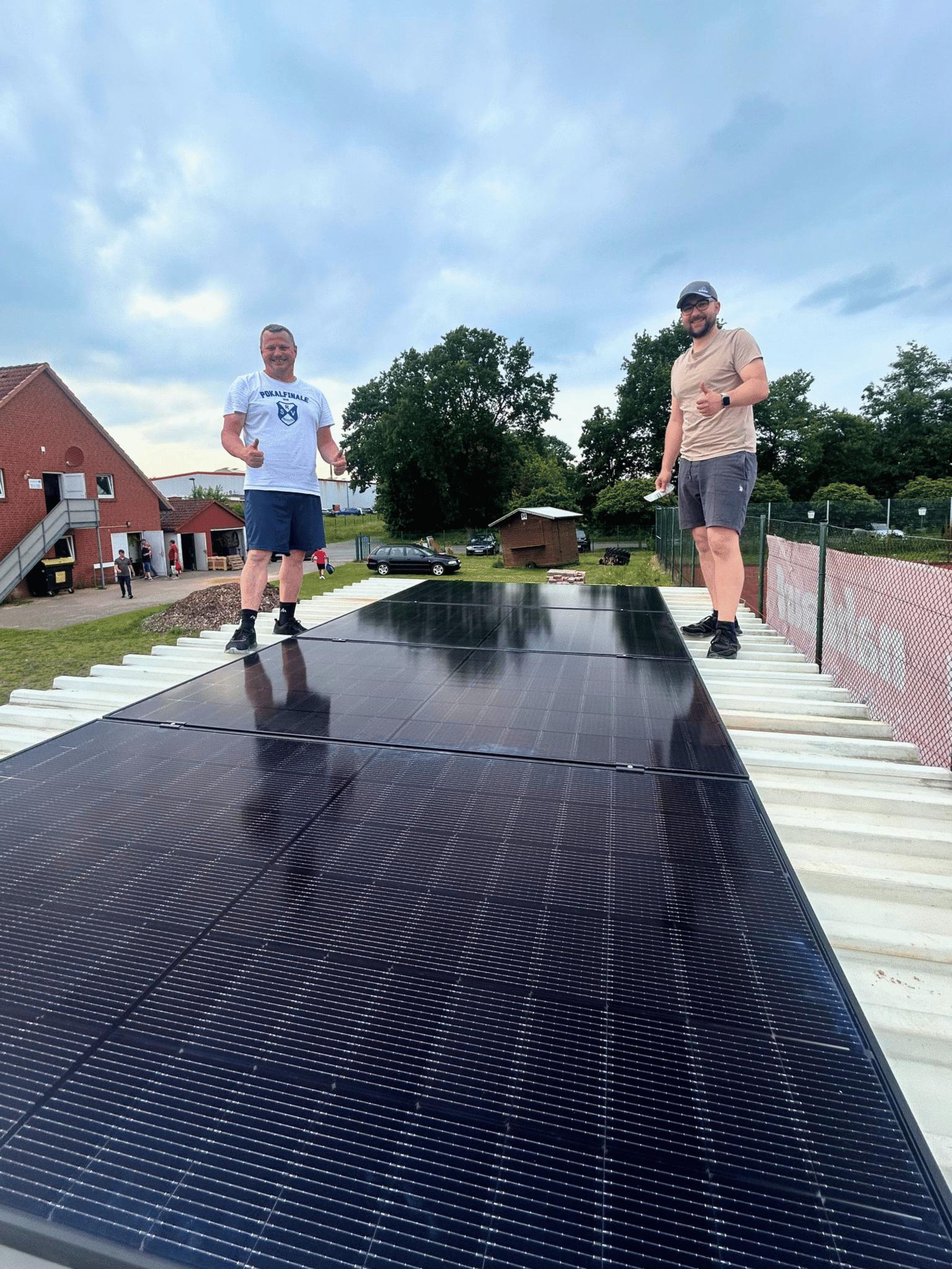 Zwei Männer stehen auf dem Dach neben einem fertig montierten Solarpanel.