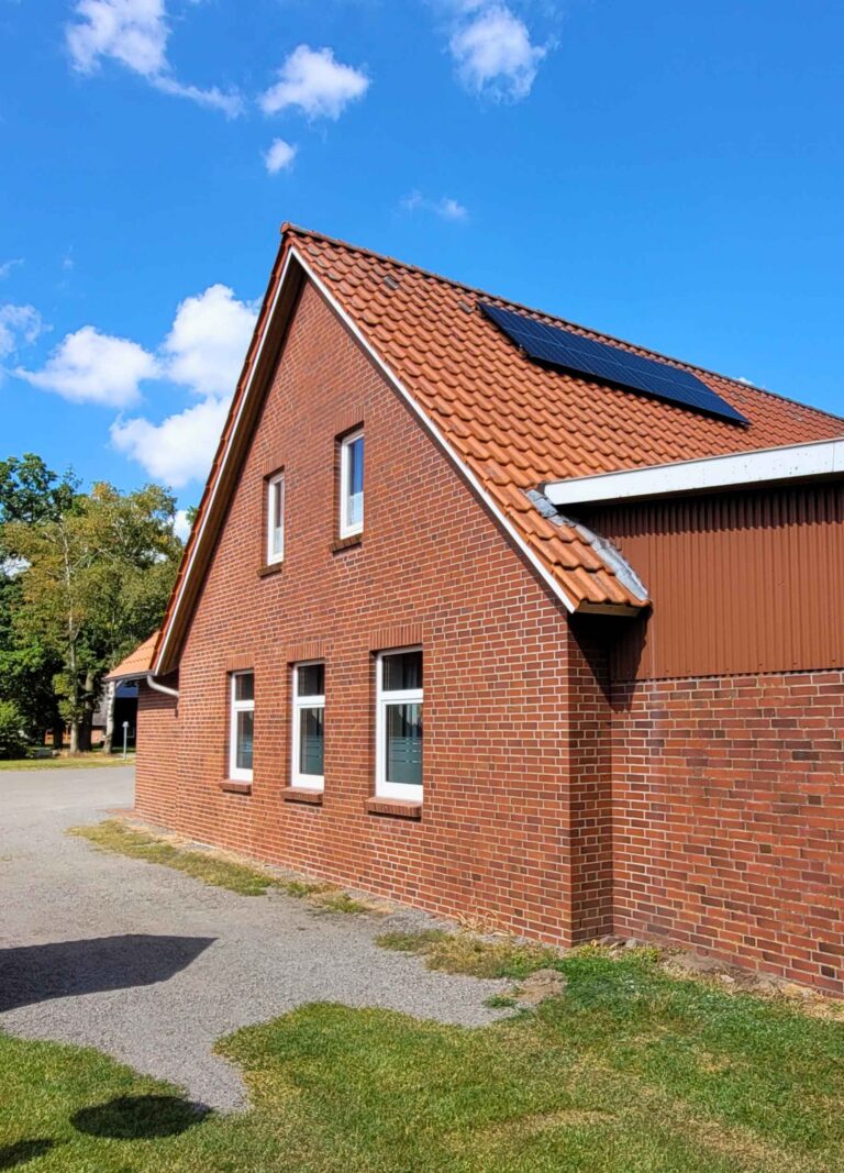 Das Vereinsheim des Sportvereins aus roten Ziegeln und mit einer Balkon-Solatranlage auf dem Dach.
