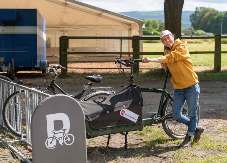 Eine Frau lehnt an einem Lasten-Fahrrad an den neuen Fahrradständern auf dem Vereinsgelände.